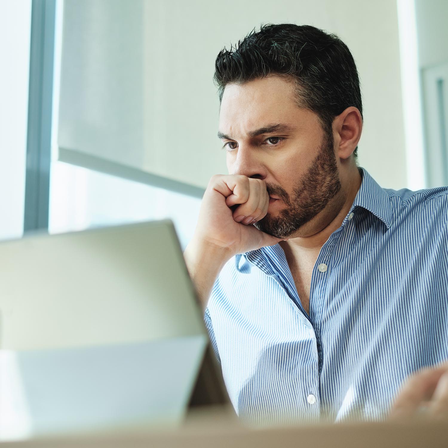 Angry Hispanic businessman working with laptop computer in office, losing patience. Anxious executive man under stress at work for technology problems and software pc virus