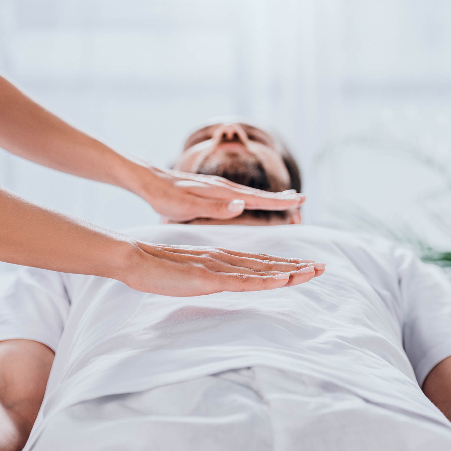 A man with a Reiki practitioner's hands hovering above him.