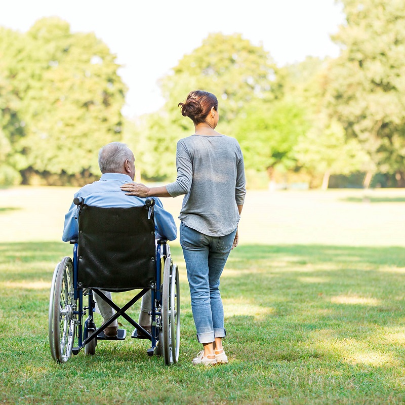 Senior man sitting on a wheelchair with caregiver