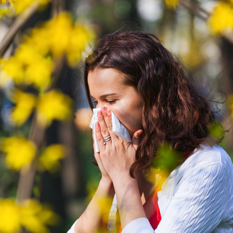 Woman outside blowing her nose in a tissue