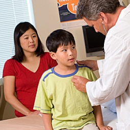 A doctor looks at a child patient while the mother observes.