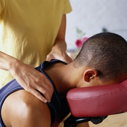 Massage therapist giving man a seated massage