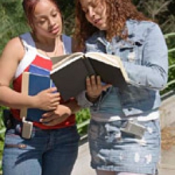 Two teen girls reviewing a book.