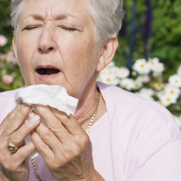 A woman outside prepares to sneeze.