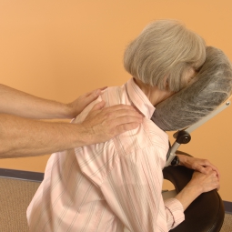 A woman receives seated massage.