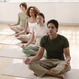 People in a meditative pose during a class on mats.