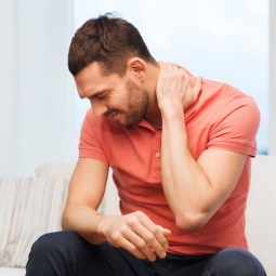 A man holds his neck in pain.