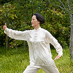 A woman practices Tai Chi outside.