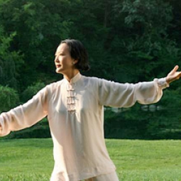 A woman practices Tai Chi outside.