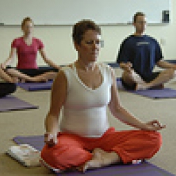 Participants in a yoga class meditating while in the lotus pose.