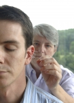 Acupuncturist inserts needles into a man's ear.