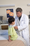 A doctor examines a boy. A Time to Talk poster is in the background.