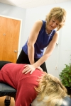A chiropractic doctor provides an adjustment to a woman on a table.