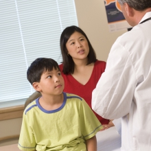 A mother and son talk to a doctor.