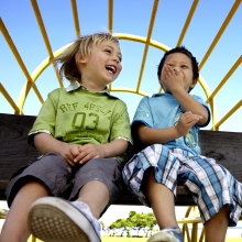 Two boys laughing while sitting on playground equipment