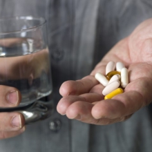 Dietary Supplements in hand with glass of water