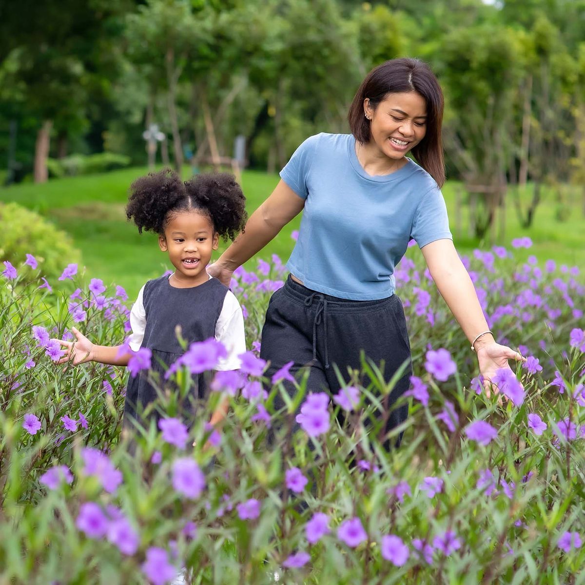 A woman and a child outdoors around flowers