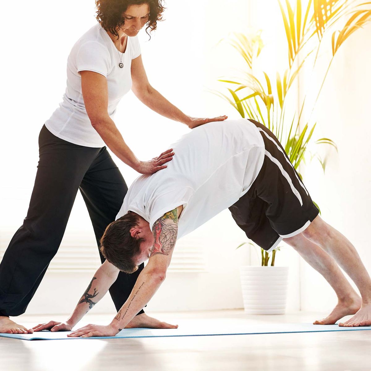 Man in downward dog yoga pose with instructor present